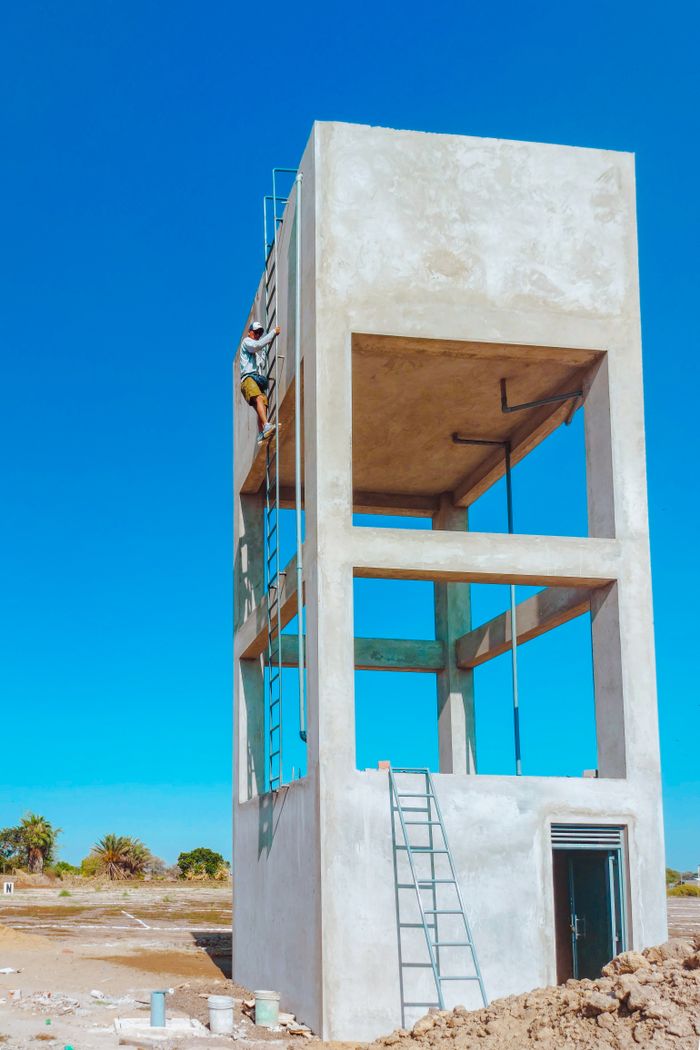 A worker climbing a ladder on a new concrete water tower in Lambayeque, Peru.
