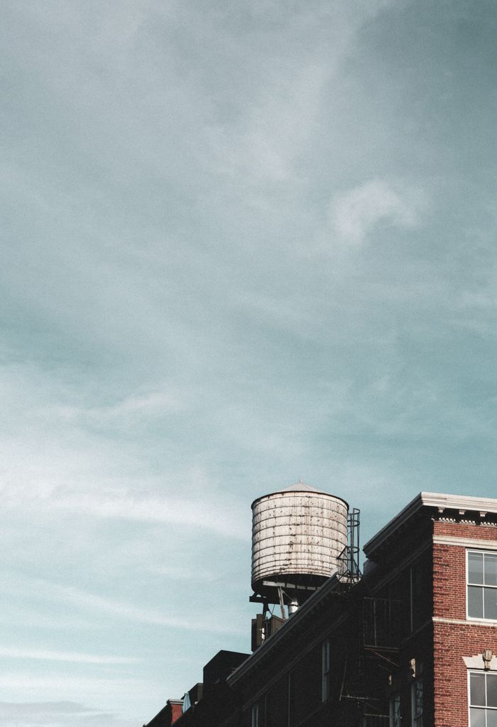 A classic water tower atop a historic building under a vast New York City sky.
