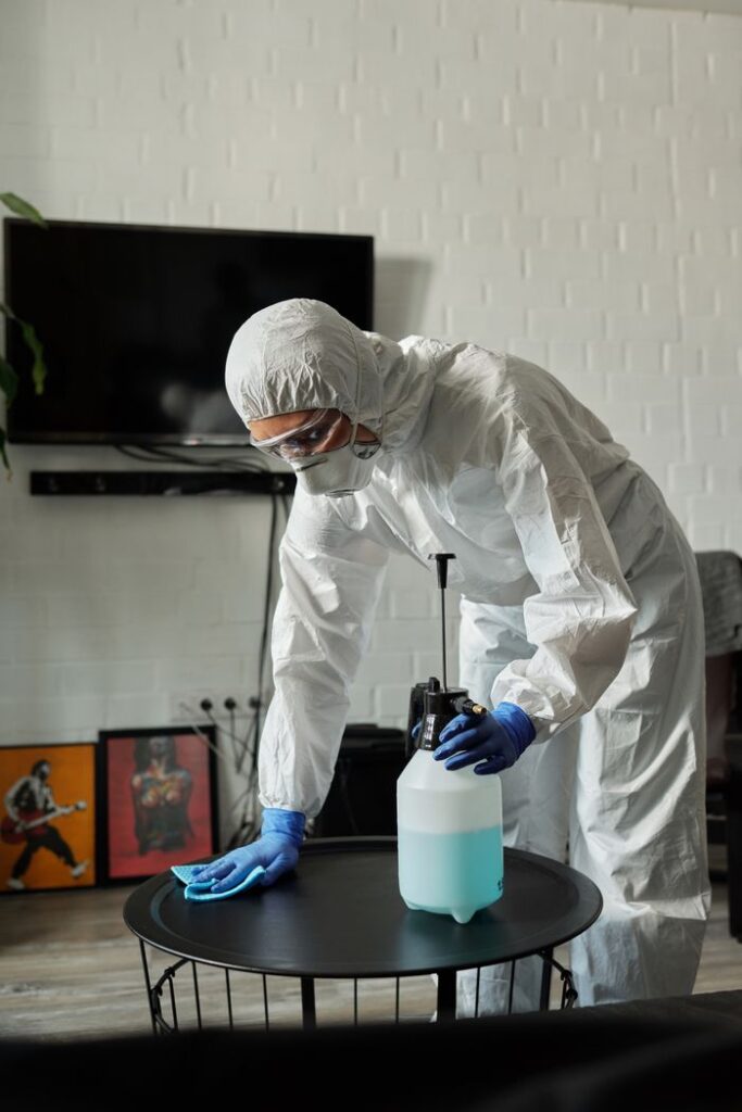 Mastering the First Impression: Your intriguing post title goes here Person in protective gear cleaning a living room table with disinfectant.