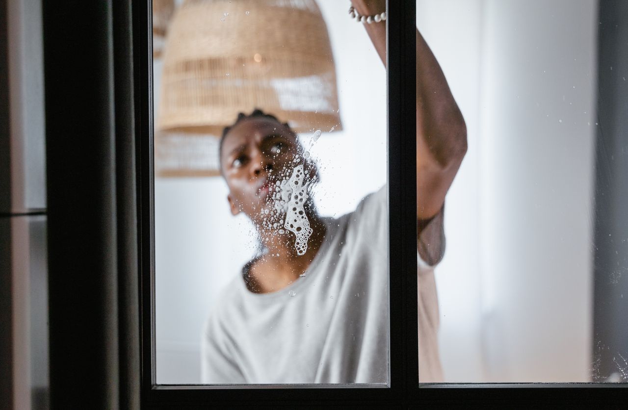 The Art of Drawing Readers In: Your attractive post title goes here An adult male cleaning a glass window indoors, focusing on household chores and cleanliness.